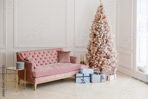 Interior with white walls and soft sofa decorated for celebrating New Year. Comfort home in Christmas Holidays