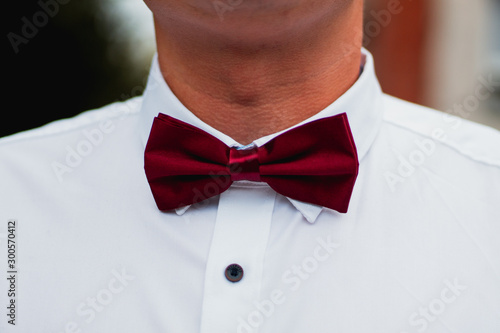 Man in a white shirt with dark red bow tie. 