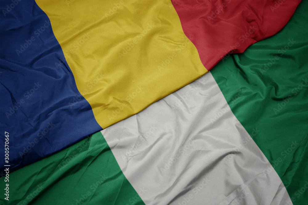 Obraz premium waving colorful flag of nigeria and national flag of romania.