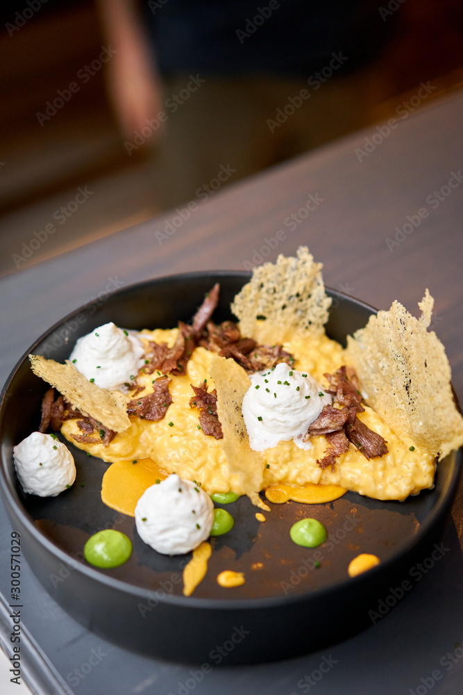 Dinner in restaurant. Pumpkin Risotto with with duck and parmesan cheese mousse. Seasonal autumnal recipe - risotto with organic pumpkins. Dinner in restaurant. Pumpkin Risotto with with duck and parmesan cheese mousse. Seasonal autumnal recipe - risotto with organic pumpkins.