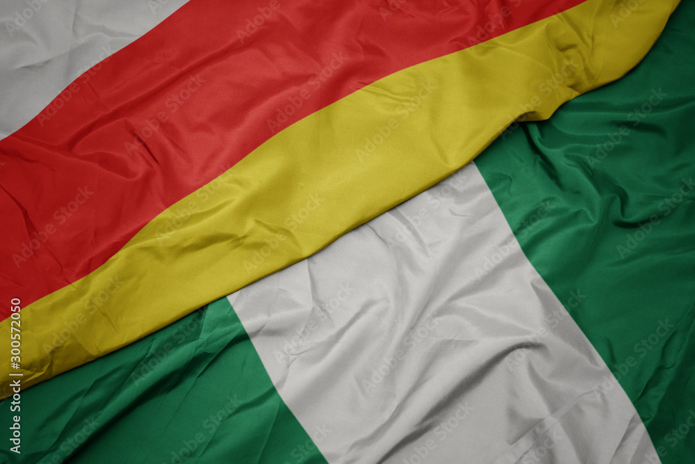 waving colorful flag of nigeria and national flag of south ossetia.