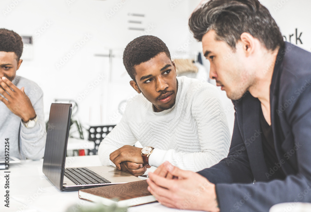 A team of young office workers, businessmen with laptop working at the table, communicating together in an office. Corporate businessteam and manager in a meeting. coworking. A team of young office workers, businessmen with laptop working at the table, communicating together in an office. Corporate businessteam and manager in a meeting. coworking.