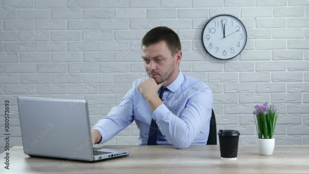 Businessman sitting at office desk working on laptop computer