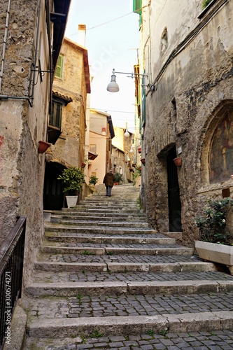 Old man climbing up the stairs in a medieval village in Italy