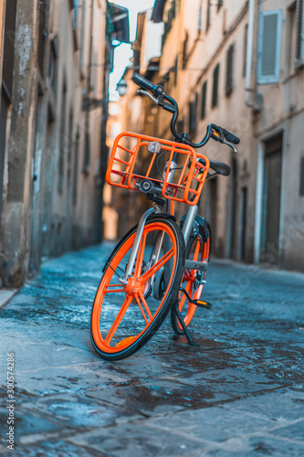Orange bike parked in the street of Florence historical center, in Italy photo