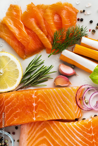 fresh seafood on a table with spices, vegetables and olive oil: fresh and smoked salmon, shrimp and crab sticks for a supermarket or fish sushi restaurant.