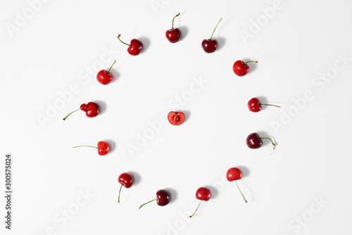 Cherry berry in the center of a circle from ripe cherries on a white surface.Top view.