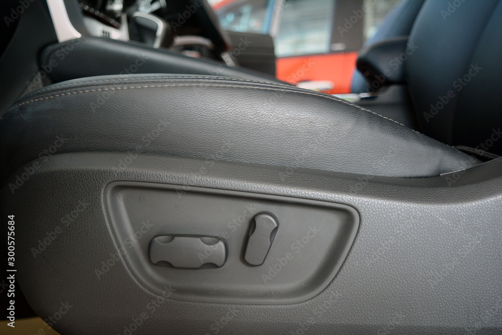 the seat level adjust button beside the grey leather seat in the car the seat level adjust button beside the grey leather seat in the car