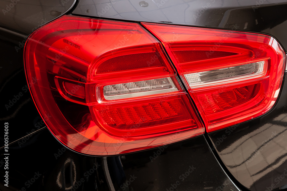 Close-up on the rear LED brake light of red color on a black car in the back of a suv after cleaning, polishing and detailing in the vehicle repair workshop. Auto service industry. Stop concept