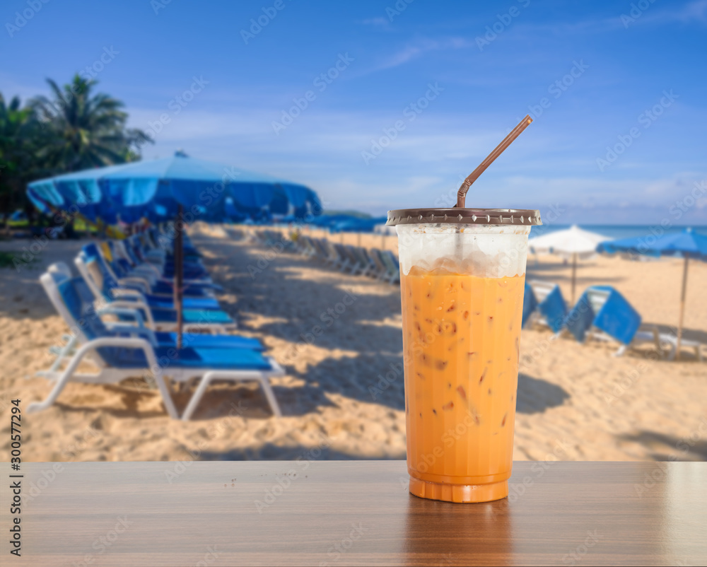 Ice milk coffee with blurred beach sand and blue sea and blue sky