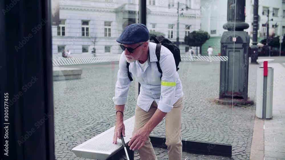 Senior blind man with white cane waiting at bus stop in city. Senior blind man with white cane waiting at bus stop in city.