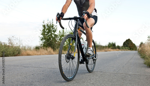 The cyclist is training on his road bike outside the city by asphalt road