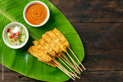 Pork satay - Grilled pork served with peanut sauce or sweet and sour sauce on Banana leaf - Asian food style on wood table