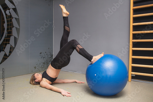 Fitness instructor demonstrates how to do the exercises in a gym with fitness ball