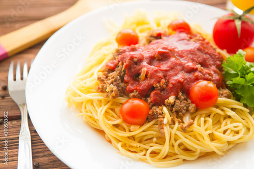 Spaghetti bolognese with tomatoes on a wooden background