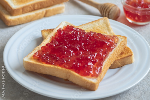 Toast bread with strawberry jam on plate .