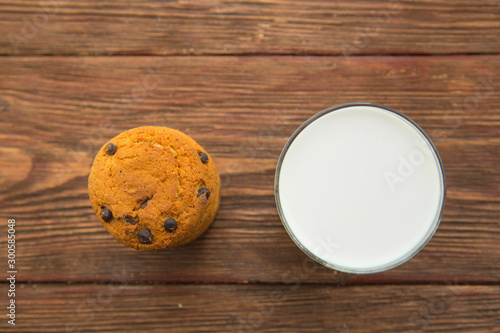 Chocolate chip cookies and a glass of milk on wooden table. Horizontal view from above.