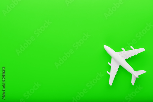 White passenger model airplane on a bright green background. Free space for text.