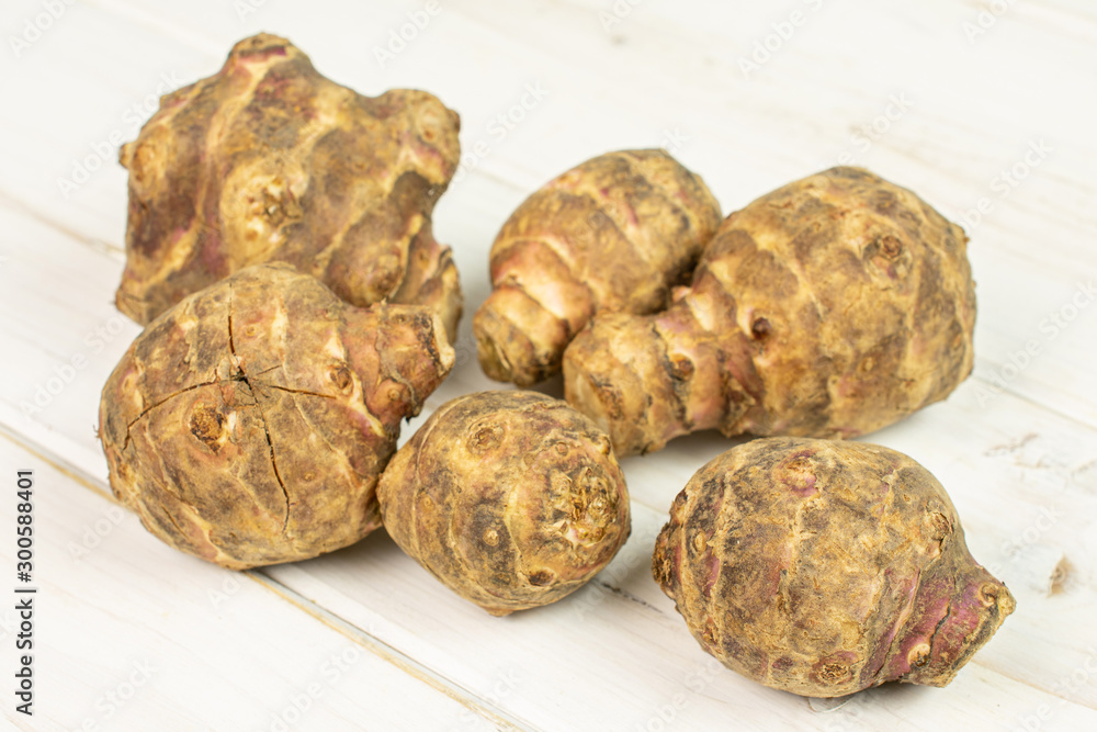Group of six whole fresh brown jerusalem artichoke on white wood Group of six whole fresh brown jerusalem artichoke on white wood
