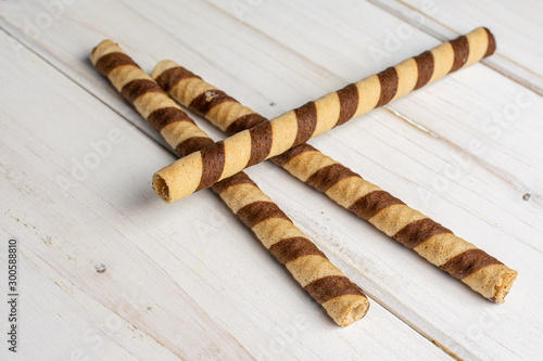 Group of three whole crunchy beige hazelnut rolled wafer biscuit on white wood