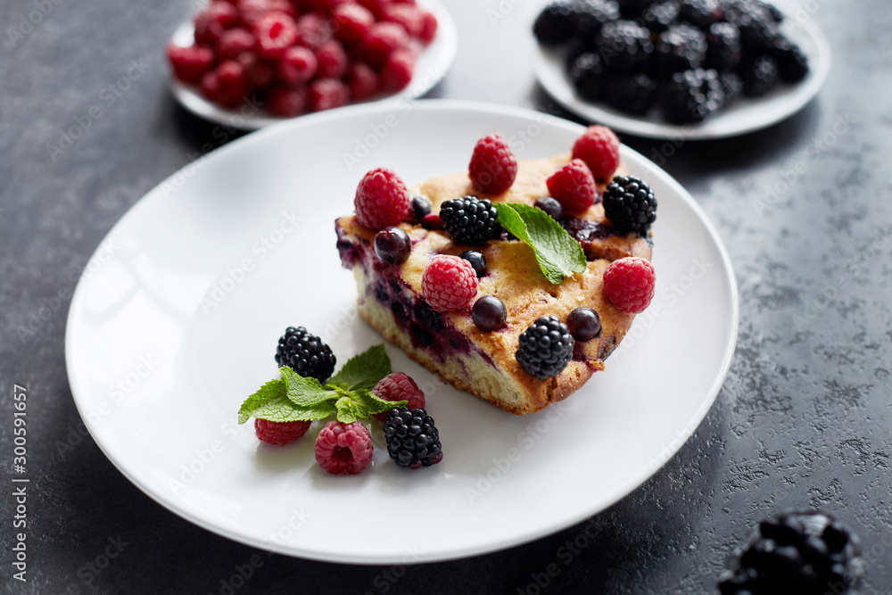 Piece of pie with blueberries, raspberry and mint for dessert on a white plate. Pieces of delicious homemade cake on a background Piece of pie with blueberries, raspberry and mint for dessert on a white plate. Pieces of delicious homemade cake on a background