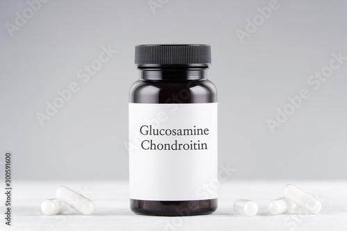 nutritional supplement glucosamine and chondroitin bottle and capsules on gray photo