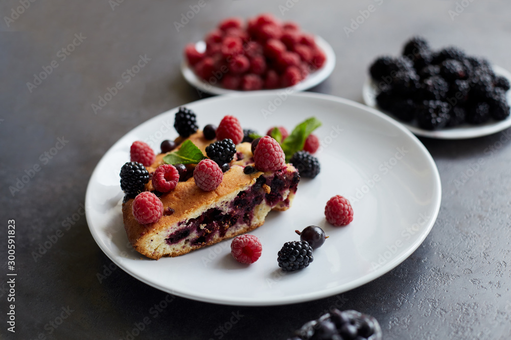 Piece of pie with blueberries, raspberry and mint for dessert on a white plate. Pieces of delicious homemade cake on a background Piece of pie with blueberries, raspberry and mint for dessert on a white plate. Pieces of delicious homemade cake on a background