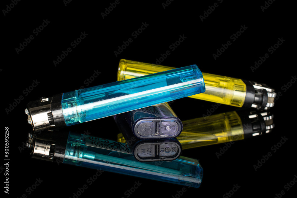Group of three whole plastic lighter isolated on black glass