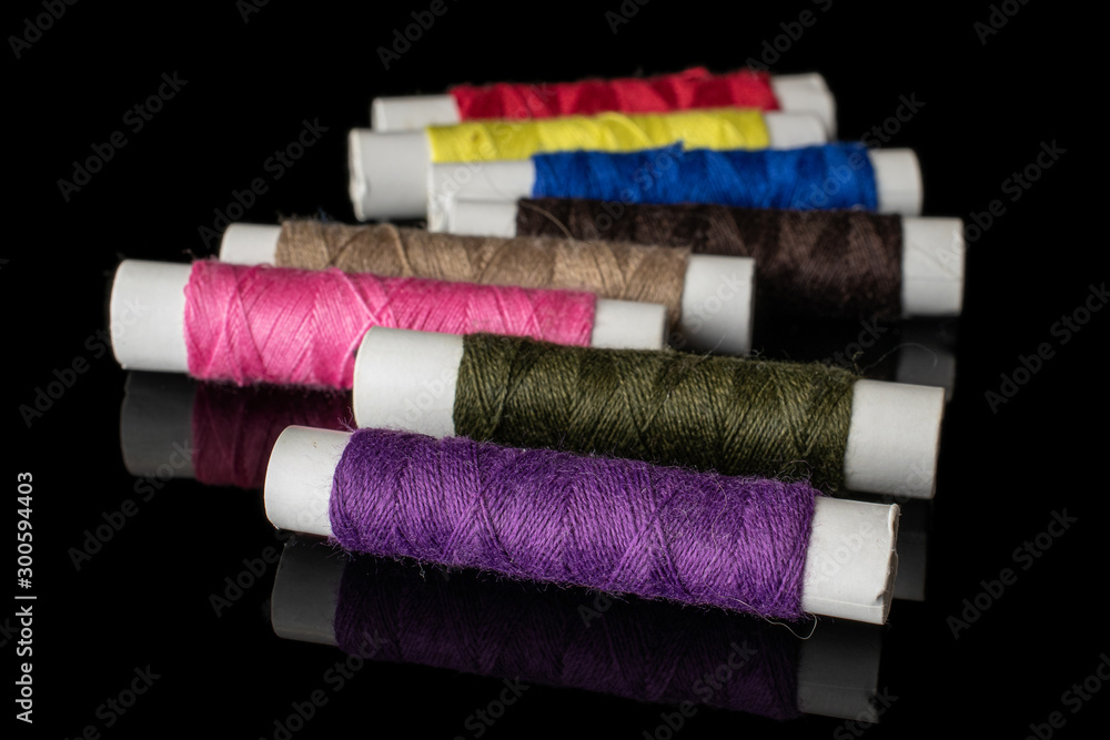 Group of eight whole sewing thread spool isolated on black glass Group of eight whole sewing thread spool isolated on black glass