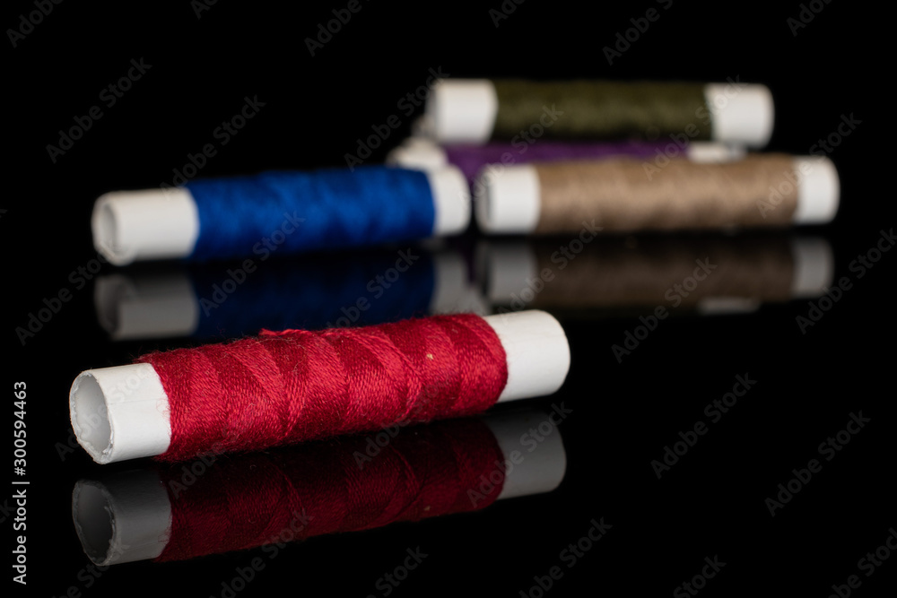 Group of five whole sewing thread spool isolated on black glass Group of five whole sewing thread spool isolated on black glass