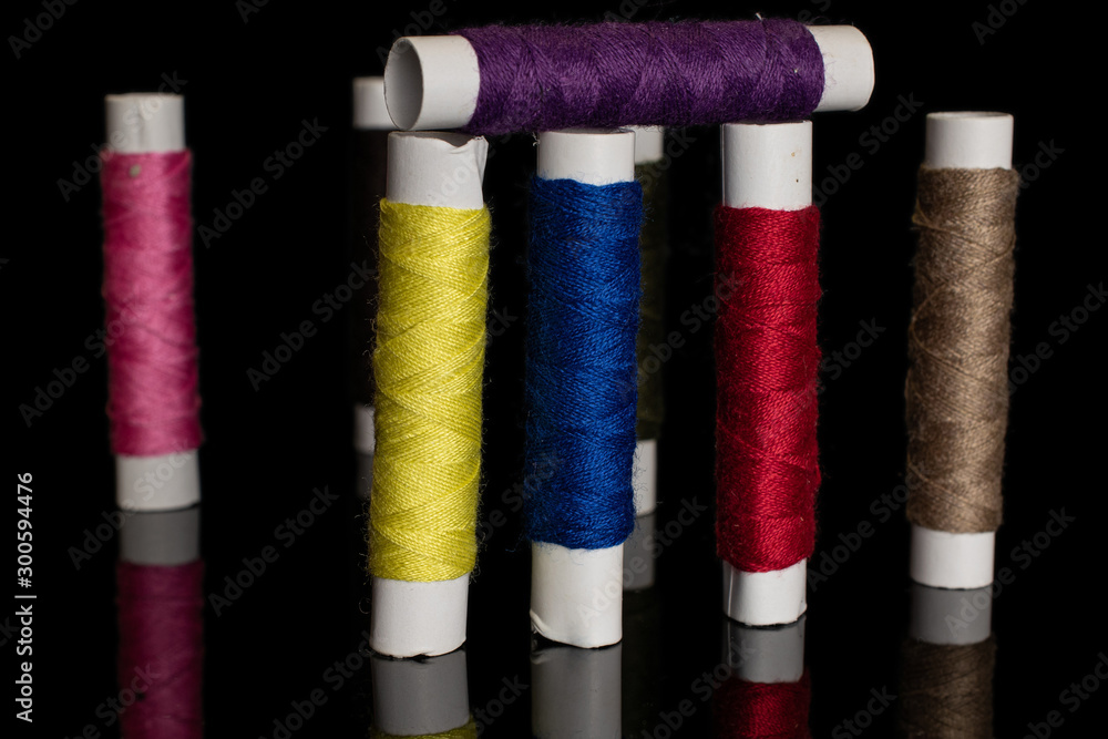Group of eight whole standing sewing thread spool isolated on black glass Group of eight whole standing sewing thread spool isolated on black glass