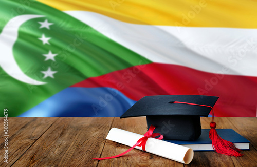 Comoros education concept. Graduation cap and diploma on wooden table, national flag background. Succesful student. photo