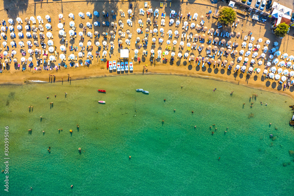 sandy beach with sunbeds and umbrellas, lot of bathing and resting people, view from drone, Greece, Rhodes. Europe