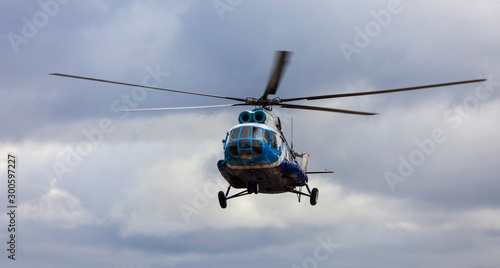 Helicopter in blue and white colors against a cloudy sky.