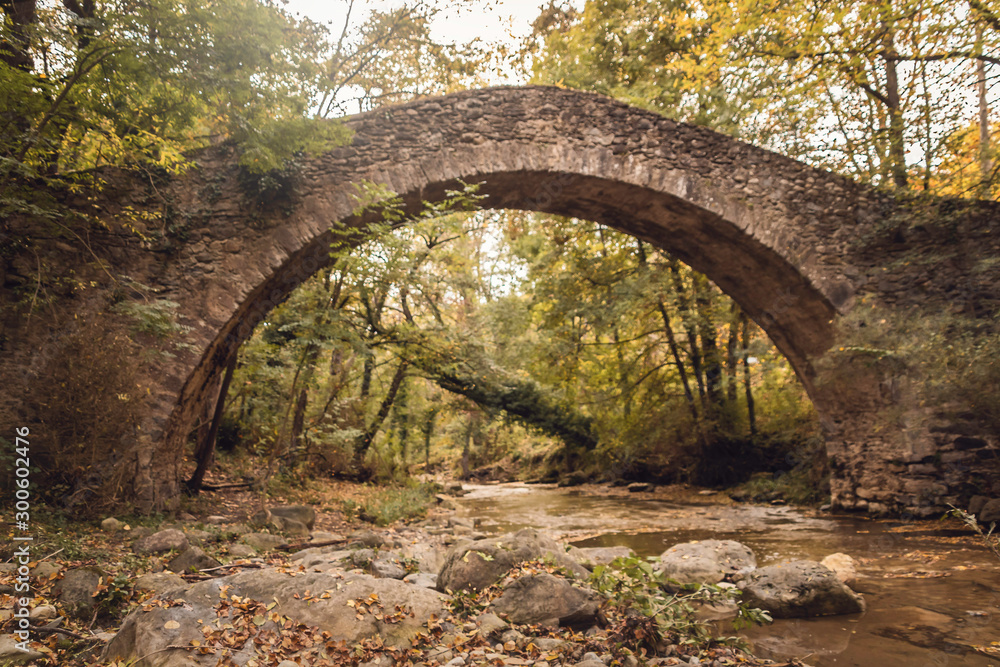 Medieval bridge over a river in a wooded setting in autumn Medieval bridge over a river in a wooded setting in autumn
