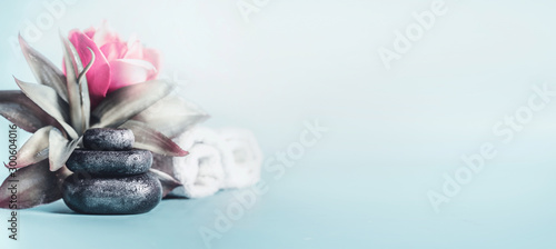Spa and wellness concept with stack of zen stones, flowers and towels at light blue background with copy space. Relax and calm  treatment. Still life. Banner