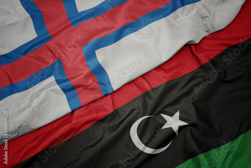 waving colorful flag of libya and national flag of faroe islands.