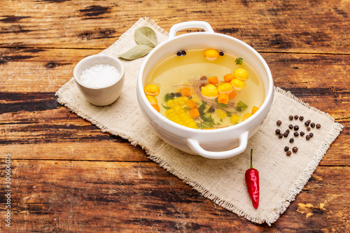 Transparent duck broth with dumplings and vegetables. Traditional bouillon, healthy food. Old wood background