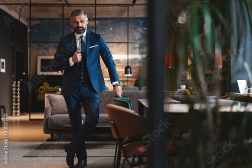 Fotografia Stylish bearded man in a suit standing in modern office