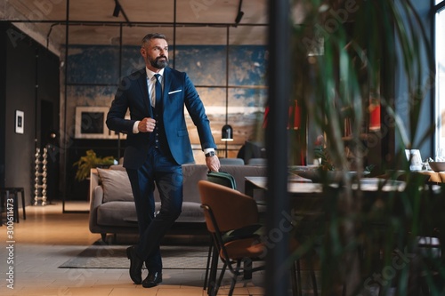 Fototapeta Stylish bearded man in a suit standing in modern office