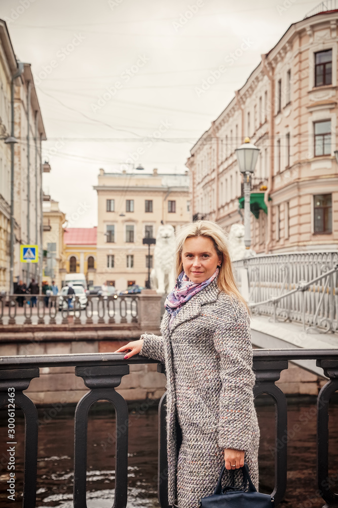 Fototapeta premium Portrait of a young woman walking along the canal in St. Petersburg in autumn