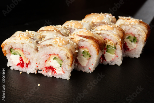 Sushi Rolls with cucumber, flying fish caviar, eel, omelet and Cream Cheese inside on black slate isolated. Philadelphia unagi roll sushi with tamago. Sushi menu. Horizontal photo.