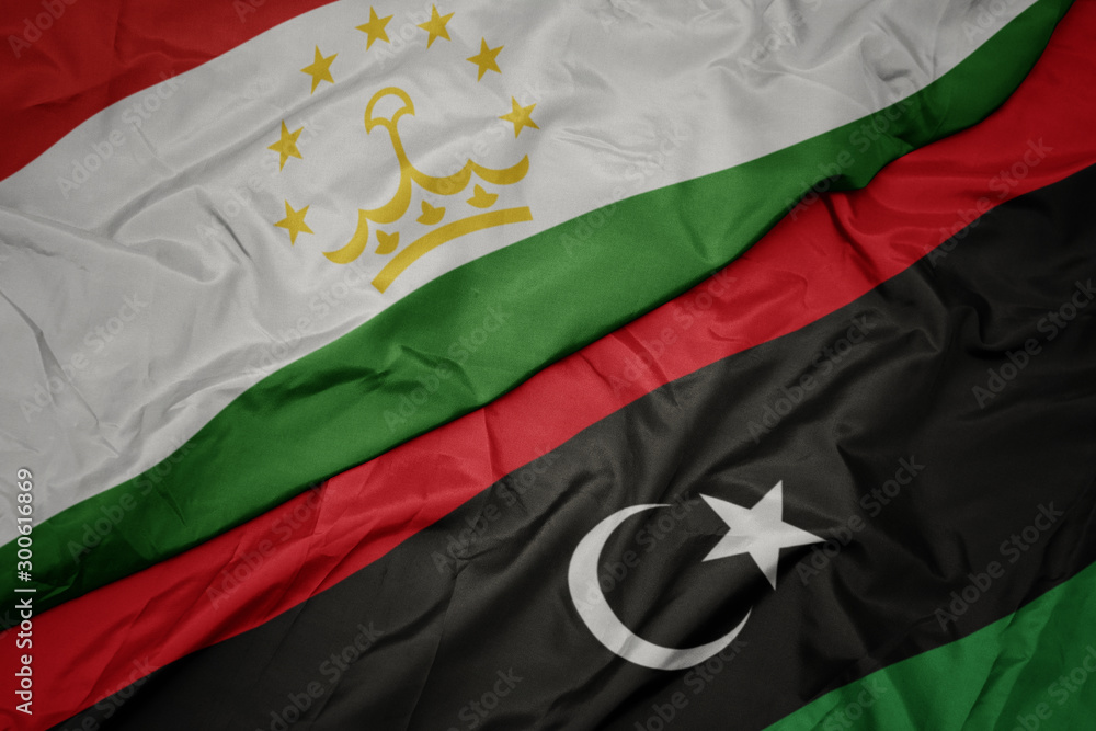 waving colorful flag of libya and national flag of tajikistan. waving colorful flag of libya and national flag of tajikistan.