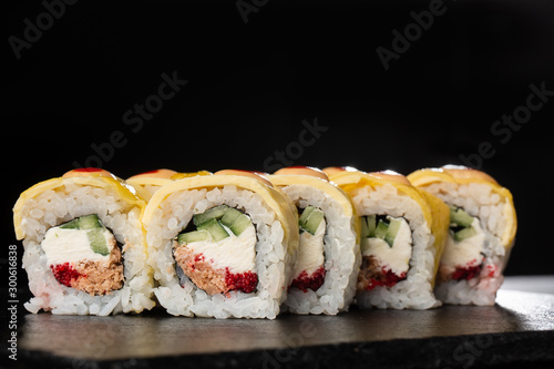 Sushi Rolls with cucumber, cheddar, flying fish caviar , tuna and Cream Cheese inside on black slate isolated. Philadelphia cheddar roll sushi with tuna. Sushi menu. Horizontal photo.