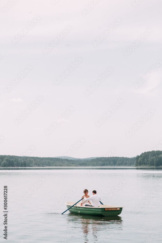  Stylish wedding in European style. Happy couple on a boat on the lake.