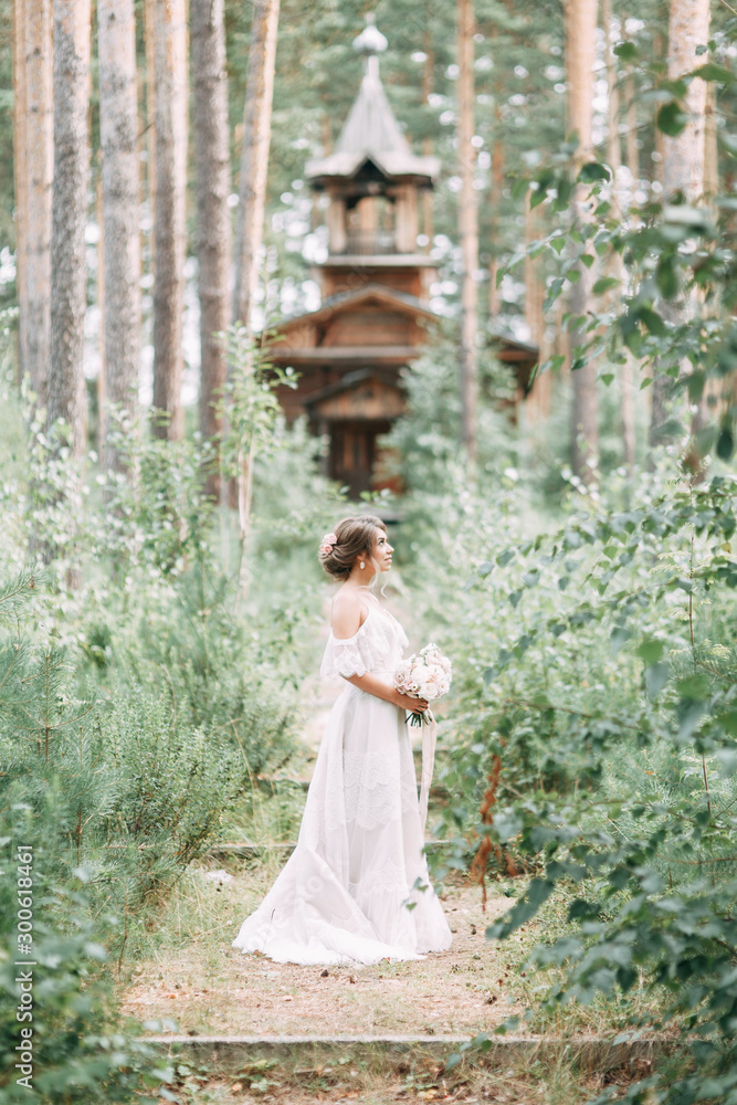 Fototapeta premium Elegant ceremony in European style. Beautiful bride in white flying dress in the forest.