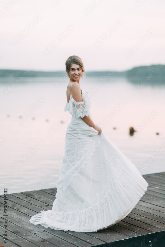 Wedding dress in European style. Happy bride at sunset on the lake. Wedding dress in European style. Happy bride at sunset on the lake.