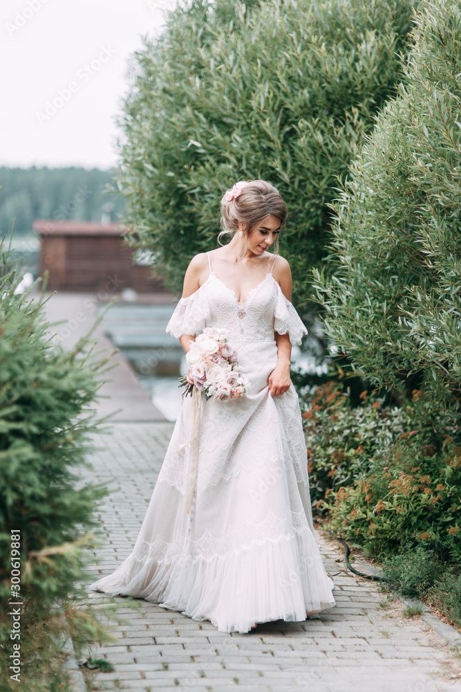 Stylish European-style wedding in nature. Happy bride on the pier on the lake.