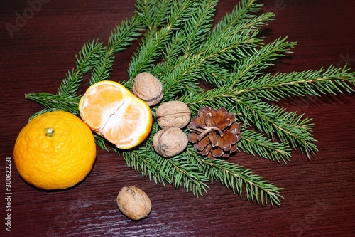 Spruce branches, cones and tangerines with nuts on the background