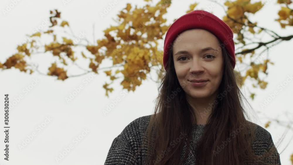 Portrait of smiling girl posing outdoors on autumn nature sky background copy space. Front view of young woman looking to camera with happy smile slow motion. Female beauty cosmetics product